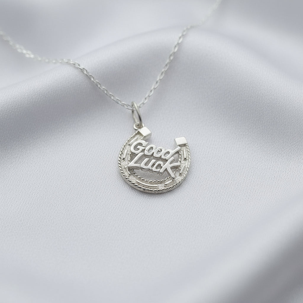 Silver necklace with 'Good Luck' pendant on a white fabric background
