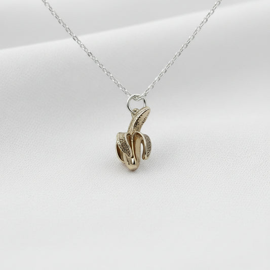 Gold and silver banana pendant on a white background