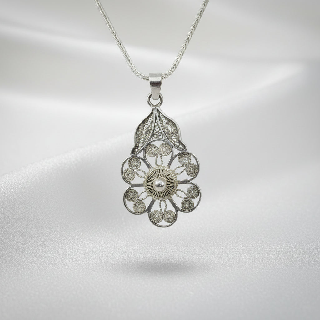 Silver filigree pendant on a chain against a light gray background