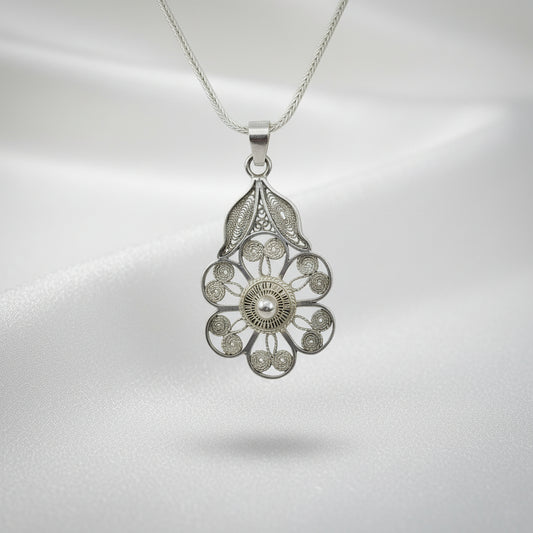 Silver filigree pendant on a chain against a light gray background
