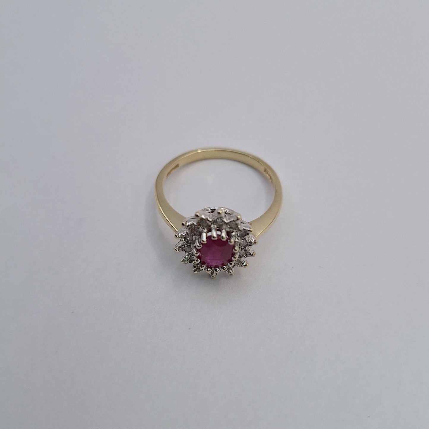 Gold ring with a pink gemstone and diamond accents on a light gray background